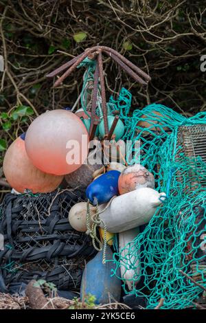 Alte Angelwagen und Fishermans-Utensilien mit rostigen alten Ankern, Drähten und Leinen mit Netzen, die an einem Fishermans-Kai zum Trocknen hängen Stockfoto