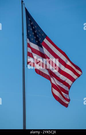 Amerikanische Flagge winkt gegen einen hellen blauen Himmel – patriotisches Stockbild Stockfoto