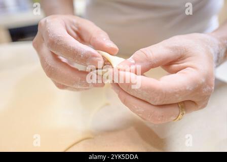 In einer hellen Küche bereitet man gekonnt traditionelle Teigtaschen mit Fleischfüllung zu, die sich darauf konzentrieren, die Leckerei mit Sorgfalt zu gestalten. Stockfoto