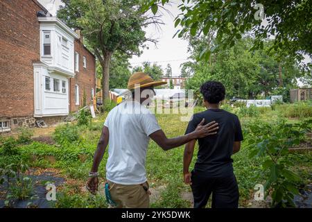 Die University of Maryland Extension Urban Farmer Field School veranstaltet eine Bildungsveranstaltung auf der Plantation Park Heights Urban Farm (PPHUF) in Baltimore, MD., am 20. Juli 2021. PPHUF wurde von Farmer Chippy (links) und einer Gruppe karibischer/amerikanischer Bürger gegründet, die Veränderungen herbeiführen und einen positiven Einfluss auf das Leben junger Erwachsener wie Farm Hand Elijah Bailey, 17, (rechts) haben, die in der Park Heights-Gemeinde leben und sich auf die Nahrungsmittelproduktion und -Verteilung konzentrieren, um die erste „Agrihood“ in Baltimore, MD, zu schaffen USDA/FPAC Foto von Preston Keres Stockfoto