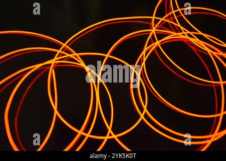 Ungewöhnliches, dünnes rotes Gewinde, verdrillter Draht, strukturelles und gebogenes Kabel. Neon-Elektrolumineszenzkabel, Draht, Kunststoff strahlt Neonlicht gleichmäßig aus. Stockfoto