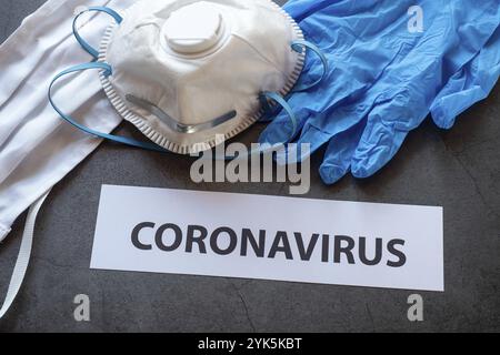 Textsatz Coronavirus auf schwarzem Hintergrund mit Schutzmasken, Handschuhen und Atemschutzmasken FFP2 für Coronavirus-Epidemie Stockfoto