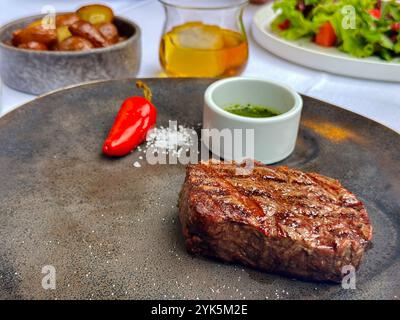 Ein mittelgroßes gebratenes Steak auf einem Teller serviert mit gebratenen Kartoffeln und einem Salat, Krakau, Polen Stockfoto