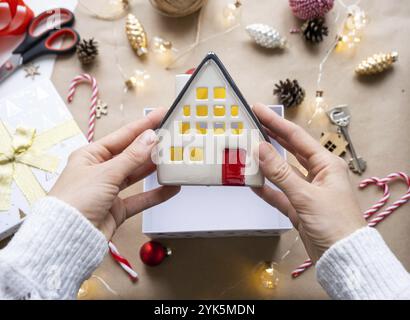 Schlüssel zum Haus mit Schlüsselanhänger auf gemütlichem Zuhause in Geschenkbox mit Weihnachtsdekor-Verpackung. Pack ein Geschenk für Neujahr, Weihnachten. Gebäude, Projekt, Umzug nach Stockfoto