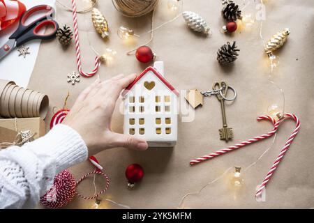 Schlüssel zum Haus mit Schlüsselanhänger auf einem gemütlichen Zuhause mit weihnachtlicher Dekoration. Ein Geschenk für Neujahr, Weihnachten. Gebäude, Design, Projekt, Umzug nach NE Stockfoto