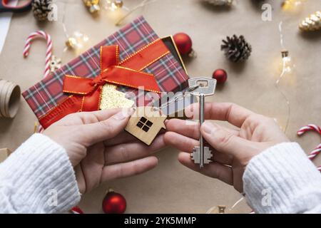 Schlüssel zum Haus mit Schlüsselanhänger auf gemütlichem Zuhause in Geschenkbox mit Weihnachtsdekor-Verpackung. Pack ein Geschenk für Neujahr, Weihnachten. Gebäude, Projekt, Umzug nach Stockfoto