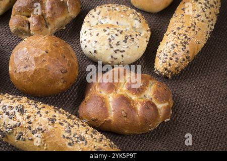 Verschiedene Arten von Vollkorn Brot und Brötchen auf braunem Hintergrund Stockfoto