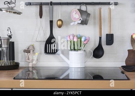 Innenausstattung der Küche und Details der Einrichtung von Utensilien mit Osterdekoration aus bunten Eiern im Loft-Stil. Festliches Innere eines Landhauses Stockfoto