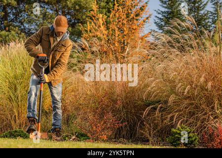 Ein Gärtner gräbt sich in den Boden, um neues Grün in einer farbenfrohen Landschaft mit Herbstlaub zu Pflanzen. Stockfoto