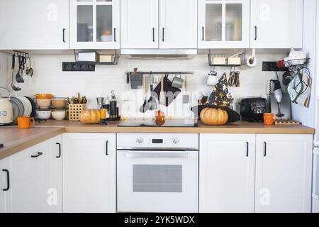 Dekor der weißen klassischen Küche mit Kürbissen für Halloween und Ernte. Herbststimmung im Innenraum, moderner Loft-Stil Stockfoto