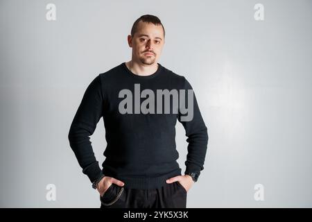 Porträt eines selbstbewussten Mannes in einem schwarzen Pullover vor neutralem Hintergrund. Stockfoto