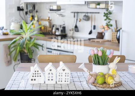 Schlüssel zum Haus eines gemütlichen Hauses mit Osterdekor mit Hase und Eiern auf dem Tisch der Küche. Gebäude, Entwurf, Projekt, Umzug in ein neues Haus, Hypothek, Versicherung Stockfoto