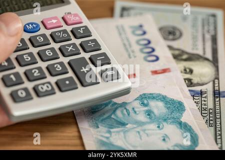 Geld argentinischer Wechselkurs, Peso vs Dollar. Finanzkonzept. Neue 10.000 Tausend argentinische Pesos und 100 US-Dollar, Taschenrechner in der Hand. Nahaufnahme Stockfoto