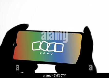 Person, die ein Mobiltelefon mit dem Logo des indischen Technologieunternehmens Zoho Corporation auf dem Telefonbildschirm hält Stockfoto