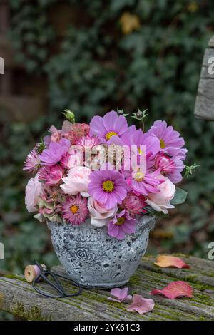 Blumenarrangement mit rosa Kosmos Blumen, Rosen, strohblumen, japanischer Anemone und Hortensie in einem Vintage-Topf Stockfoto