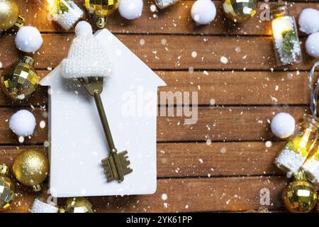 Schlüssel zum Haus mit Schlüsselanhänger winziges Haus auf hölzernem Hintergrund mit weihnachtlichem Dekor. Geschenk für Neujahr, Weihnachten. Bauen, Projekt, Umzug nach ne Stockfoto