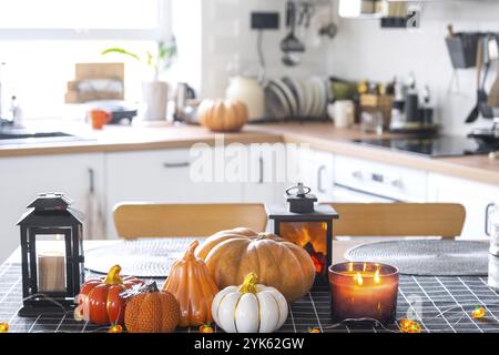 Dekor der weißen klassischen Küche mit Kürbissen, Girlanden, Latern für Halloween und Ernte mit Hausfigur. Herbststimmung im Innenraum, modern Stockfoto