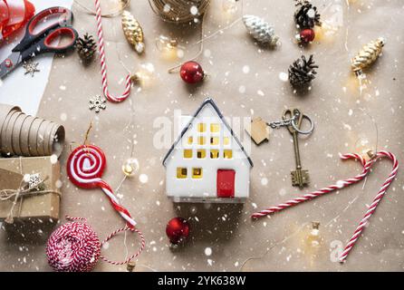 Schlüssel zum Haus mit Schlüsselanhänger auf einem gemütlichen Zuhause mit weihnachtlicher Dekoration. Ein Geschenk für Neujahr, Weihnachten. Gebäude, Design, Projekt, Umzug nach NE Stockfoto