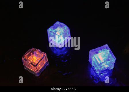 Wunderschöner und leuchtend blauer Eiswürfel schwimmt in einem Glas Sektglas mit einem Getränk. Plastikgegenstände in Form von Eiswürfeln. Stockfoto