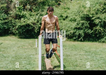Fitter Mann, der draußen trainiert, ein Trizepsbad in der Natur macht Stockfoto