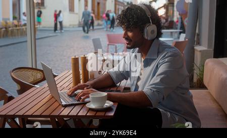 Indischer arabischer Mann männlicher Geschäftsmann Kunde Geschäftsmann Online-Arbeit im Café Fernunterricht mit Geräten Laptop Telefon Musik in Kopfhörern hören Stockfoto