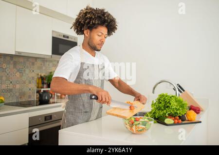 Ein Mann bereitet frisches Gemüse in einer modernen Küche an einem sonnigen Tag zu Stockfoto