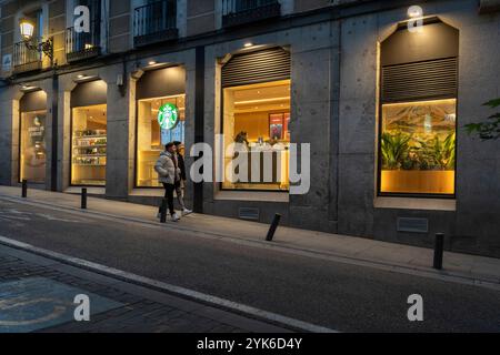 Die Fenster eines Starbucks Coffee Shops werden am frühen Morgen in der Nähe des Plaza Mayor in Madrid, Spanien, beleuchtet. Stockfoto