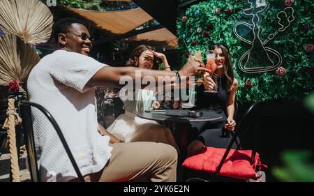 Multikulturelle Geschäftsleute genießen Drinks und feiern Erfolge in einer lebhaften Outdoor-Umgebung Stockfoto