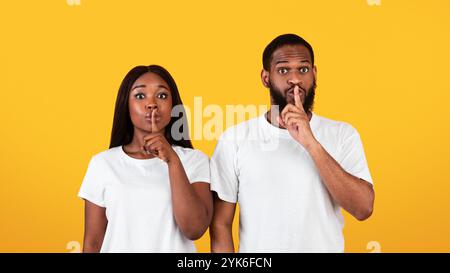 Schwarzes Paar, das Finger auf die Lippen stampft und ein Zeichen für die Stille macht Stockfoto