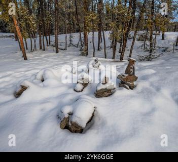 Schneebedeckter Inukshuk (Inuksuk) in einem Kiefernwald bei Yellowknife, Nordwest Territories, Kanada Stockfoto