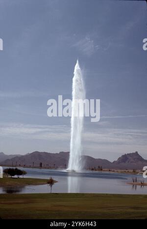 Fountain Hills, Arizona. USA 1975. Fountain Hills hat den vierthöchsten Brunnen der Welt und den zweithöchsten in den Vereinigten Staaten. Sie wurde 1970 in Zürich von Robert P. McCulloch erbaut. Das Jahr davor. Der Brunnen sprüht Wasser für ca. 15 Minuten stündlich zwischen 9:00 und 21:00 Uhr. Die Wolke erhebt sich aus einer Betonskulptur mit Seerosen in der Mitte eines großen künstlichen Sees. Der Brunnen, angetrieben von drei Turbinenpumpen mit 600 PS (450 kW), sprüht Wasser mit einer Geschwindigkeit von 7.000 US Gallonen (26.000 l; 5.800 imp gal) pro Minute durch eine 460-mm-Düse. Stockfoto