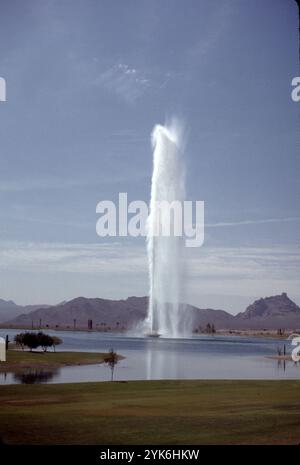 Fountain Hills, Arizona. USA 1975. Fountain Hills hat den vierthöchsten Brunnen der Welt und den zweithöchsten in den Vereinigten Staaten. Sie wurde 1970 in Zürich von Robert P. McCulloch erbaut. Das Jahr davor. Der Brunnen sprüht Wasser für ca. 15 Minuten stündlich zwischen 9:00 und 21:00 Uhr. Die Wolke erhebt sich aus einer Betonskulptur mit Seerosen in der Mitte eines großen künstlichen Sees. Der Brunnen, angetrieben von drei Turbinenpumpen mit 600 PS (450 kW), sprüht Wasser mit einer Geschwindigkeit von 7.000 US Gallonen (26.000 l; 5.800 imp gal) pro Minute durch eine 460-mm-Düse. Stockfoto