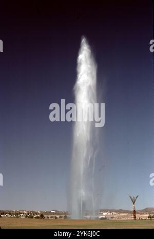 Fountain Hills, Arizona. USA 1975. Fountain Hills hat den vierthöchsten Brunnen der Welt und den zweithöchsten in den Vereinigten Staaten. Sie wurde 1970 in Zürich von Robert P. McCulloch erbaut. Das Jahr davor. Der Brunnen sprüht Wasser für ca. 15 Minuten stündlich zwischen 9:00 und 21:00 Uhr. Die Wolke erhebt sich aus einer Betonskulptur mit Seerosen in der Mitte eines großen künstlichen Sees. Der Brunnen, angetrieben von drei Turbinenpumpen mit 600 PS (450 kW), sprüht Wasser mit einer Geschwindigkeit von 7.000 US Gallonen (26.000 l; 5.800 imp gal) pro Minute durch eine 460-mm-Düse. Stockfoto