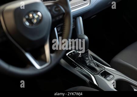 Nahaufnahme des Lenkrads und der Gangschaltung im Fahrzeuginnenraum, des Getriebes und der Tasten zur Aktivierung verschiedener Fahrzeugfunktionen. Konzentrieren Sie sich auf die Schaltflächen des Automatikgetriebes Stockfoto