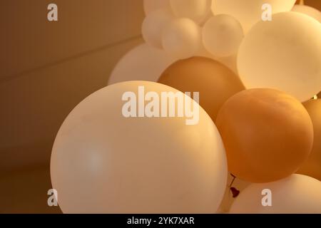 Große weiße und gelbe Ballons schmücken einen Veranstaltungssaal und sorgen für eine festliche und fröhliche Atmosphäre im Innenbereich. Stockfoto