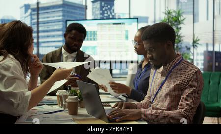 Der Enterprise Manager arbeitet mit seinen Mitarbeitern an der Erstellung einer Geschäftsstrategie und der Festlegung von Zielen, untersucht die Marktdynamik und Verkaufszahlen. Das Team des Unternehmens nimmt an einer Entwicklungsbesprechung Teil. Kamera B.. Stockfoto