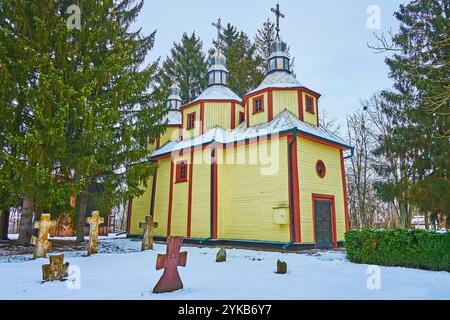 Die hölzerne Kirche und der kleine Friedhof mit kosaken-Steingrabsteinen daneben, Pereiaslav Scansen, Ukraine Stockfoto