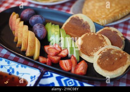 Verwöhnen Sie sich mit einem leckeren Frühstücksteller mit flauschigen Pfannkuchen und frischem Obst Stockfoto