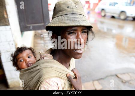 Porträt einer madagassischen Frau mit ihrem Baby an den Rücken gefesselt. Foto gemacht in Antsirabe, Madagaskar. Stockfoto