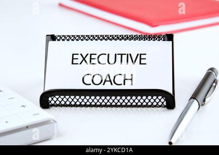 Geschäftskonzept. Der Satz, der Text, das Wort EXECUTIVE COACH stehen auf einer weißen Visitenkarte in einem Stand auf einer weißen Oberfläche. Stockfoto