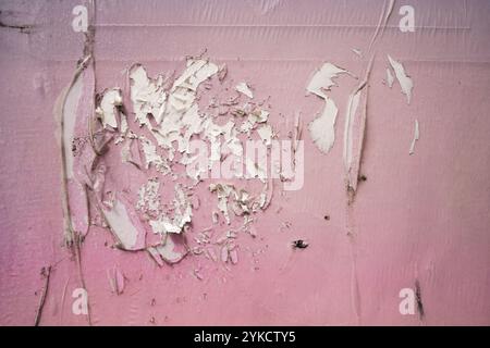 Zerkratzter rosafarbener Aufkleber auf der Wandstruktur Stockfoto