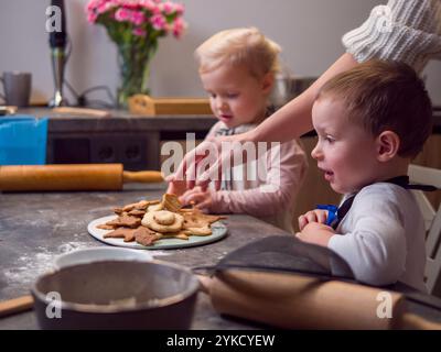 Die Familie versammelt sich in einer modernen Küche, backen und dekorieren gemeinsam weihnachtskekse, lachen und machen süße Erinnerungen. Die Freude am Schöpfen Stockfoto