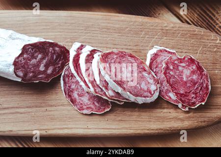 Scheiben von traditioneller spanischer Wurst, Salami oder Trockenwurst, bedeckt mit fermentierter Form auf einem Holztisch. Hochwertige Fotos Stockfoto