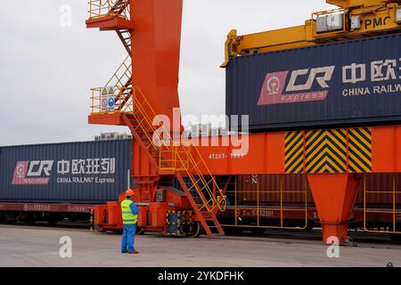 (241118) -- YIWU, 18. November 2024 (Xinhua) -- Ein Container wird am Yiwu West Railway Station in Yiwu in der ostchinesischen Provinz Zhejiang am 18. November 2024 auf einen China-Europa-Güterzug gebracht. Am Montagmorgen fuhr ein Güterzug China-Europa von der Stadt Yiwu nach Madrid, Spanien, ab und feierte den 10. Jahrestag der Inbetriebnahme dieser Strecke. Der Zug wird mit 110 TEU (TEU) verschiedener Güter, einschließlich Zubehör, Kfz-Teile, Maschinen und Ausrüstung, beladen und soll innerhalb von 16 bis 18 Tagen in Madrid eintreffen. In den letzten zehn Jahren, mehr als 6.700 China-Euro Stockfoto