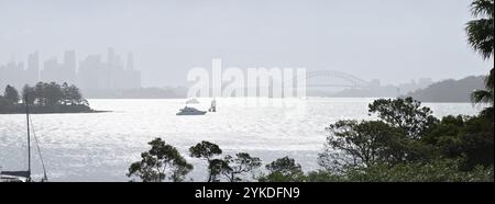 Sydney, Australien, Panoramablick auf die Sydney Harbour Bridge & Opera House unter leichtem Nebel, die Skyline des CBD in gespenstischer Silhouette und Sonnenlicht auf dem Wasser Stockfoto