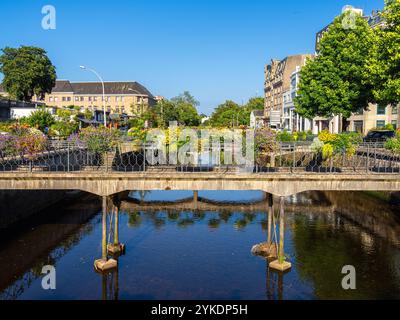 Quimper, Frankreich - 28. Juli 2024: Ein malerischer Blick auf eine Brücke in Quimper, Bretagne, geschmückt mit bunten Blumen über einem ruhigen Fluss, umgeben von Bauwerken Stockfoto