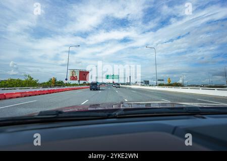 Samut Prakarn, Thailand - 9. Juli 2023, auf dem Weg zum internationalen Flughafen Suvarnabhumi. Eine fesselnde Fahrt entlang einer weiten, sonnendurchfluteten Straße unter dem Open SK Stockfoto