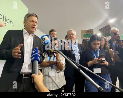 Baku, Aserbaidschan. November 2024. Robert Habeck (Bündnis 90/die Grünen), Bundesminister für Wirtschaft und Klimaschutz und Spitzenkandidat der Grünen für die Bundestagswahl 2025, spricht auf der Weltklimakonferenz. Im Hintergrund stehen Aktivisten mit Plakaten. Habeck ist trotz der Regierungskrise zur Weltklimakonferenz in Aserbaidschan gereist. Quelle: Torsten Holz/dpa/Alamy Live News Stockfoto