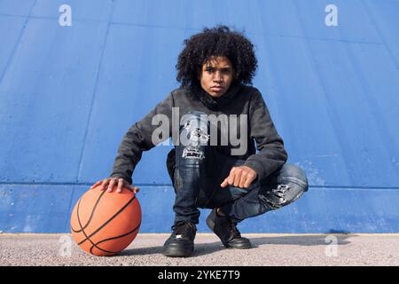teenager in ungezwungenem Outfit mit Basketballball Stockfoto