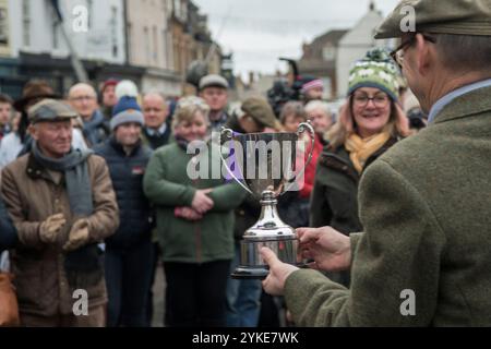 In Großbritannien erhält eine Farmerin einen Silberbecher, der auf der jährlichen Fatstock-Weihnachtsshow präsentiert wird, die in temporärer Einteilung auf einem Marktplatz in der Stadt stattfindet. Livestock, Auktionator Alastair Sneddon, überreicht einem Aussteller einen Silberbecher, der ihre Kategorie Viehzucht gewonnen hat. Uppingham, Rutland, England, 24. November 2021. HOMER SYKES Stockfoto